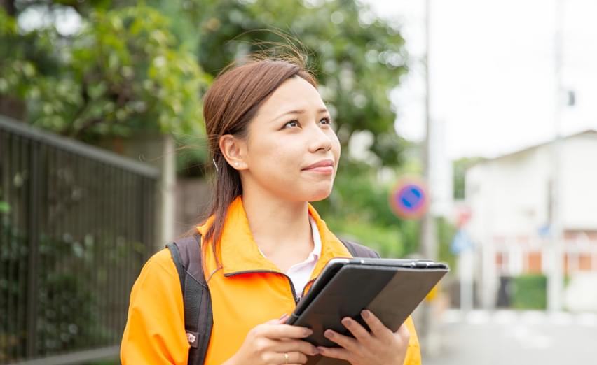 資料を手に訪問する女性スタッフ